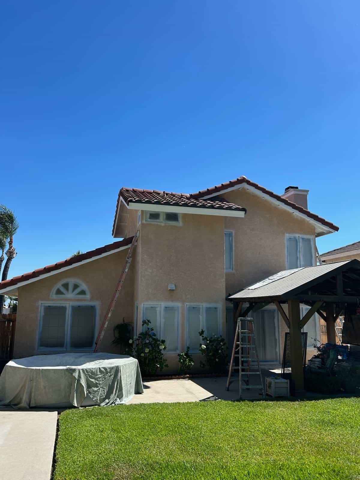 Exterior view of a house with freshly painted walls and a clear blue sky.