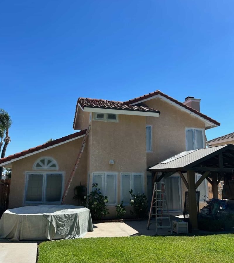 Exterior view of a house with freshly painted walls and a clear blue sky.